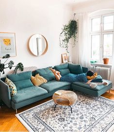 a living room filled with lots of furniture and plants on top of a rug in front of a window