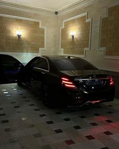 two cars are parked in the middle of a room with checkered tile flooring