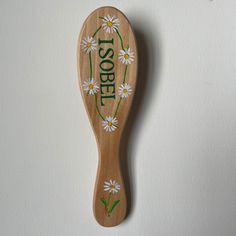 a wooden spoon decorated with daisies and the word sole written in green on it