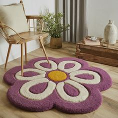 a purple and white flower rug sitting on top of a wooden floor next to a chair