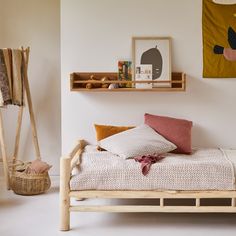 a bed with pillows and blankets on it in a room next to some wooden shelves