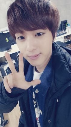 a young man making the peace sign with his hand in front of him and looking at the camera