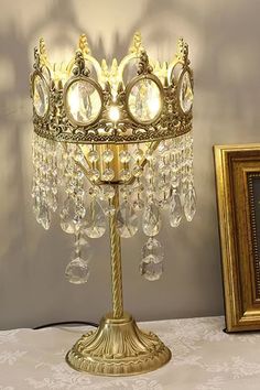 a gold colored table lamp sitting on top of a table next to a framed photo