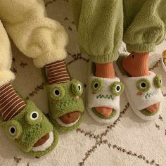 three pairs of slippers with faces on them sitting next to each other in front of stuffed animals