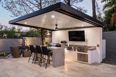 an outdoor kitchen with bar seating and television