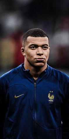 the soccer player is wearing a blue jacket and looking off into the distance with his eyes wide open