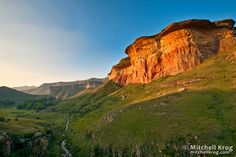 the sun shines on some mountains and valleys near a river running through them,