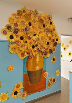 a vase filled with lots of yellow sunflowers on top of a blue wall