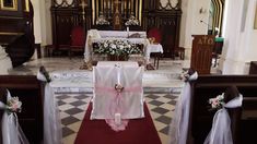 an empty church with pews and flowers on the alter, decorated for a wedding