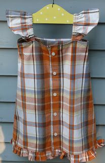 an orange and white plaid shirt hanging on a blue house with a yellow hanger