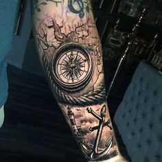 a man's arm with a compass, anchor and ship wheel tattoo on it