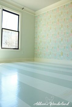 an empty room with white floors and wallpaper on the walls is painted in pastel colors