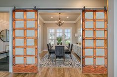 an open door leading to a dining room and living room with wood floors, white walls and windows