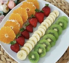 a white plate topped with sliced kiwi, oranges, strawberries and bananas