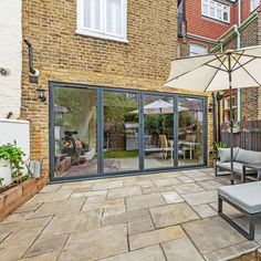 an outdoor patio with chairs and umbrellas on the side of it, next to a brick building