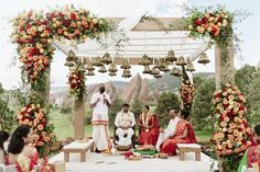 a group of people sitting on top of a white bench under an arch covered in flowers