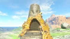 a large metal object in the middle of a field with mountains and blue sky behind it