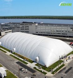 an aerial view of a large white building next to a body of water in the background