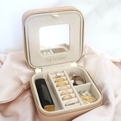 an open jewelry box sitting on top of a bed