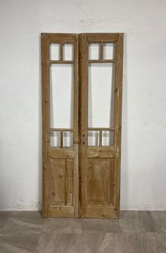 two wooden doors sitting on top of a floor next to a white wall and wood floors