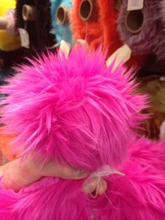 a person with pink hair is holding a stuffed animal in front of some other toys