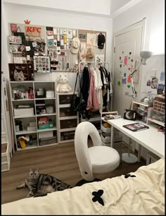 a cat laying on the floor next to a bed and desk in a small room