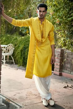 Haldi yellow kurta with mirror, thread embroidered placket and mandarin collared neckline. Paired with off-white salwar and yellow stole.
Components: 3
Pattern: Embroidery
Type Of Work: Mirror, thread
Neckline: Mandarin collar
Sleeve Type: Full sleeves
Fabric: Linen Cotton Silk
Color: Yellow
Other Details: 
Front button detailing
Side slit kurta
Occasion: Mehendi and Puja - Aza Fashions Shaadi Kurta For Men, Haldi Outfits Men, Yellow Kurta Men For Haldi, Men Haldi Outfit, Haldi Kurta For Men, Yellow Kurta Men, Kurta Design For Men, Mens Traditional Wear, Indian Wedding Clothes For Men