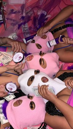 several girls in pink masks with money around them