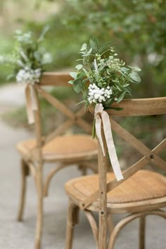 three wooden chairs with flowers tied to them