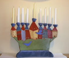 a ceramic candle holder with candles in the shape of houses and a bird on it