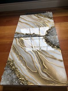 a white and gold marble table top on a wooden floor