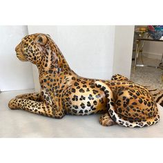 a statue of a cheetah laying down on the ground next to a mirror