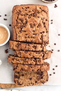 a loaf of chocolate chip banana bread on top of a cutting board next to a bowl of peanut butter