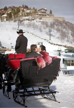 a man and woman kissing in a horse drawn sleigh on a snowy mountain