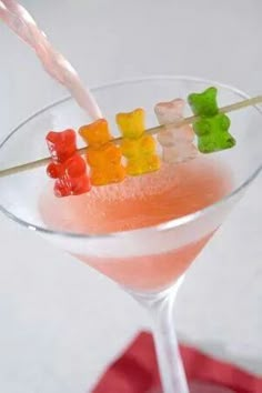 a cocktail with gummy bears on the stick sticking out of it's garnish