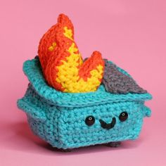 a small crocheted toy with a fish in it's stomach on a pink background