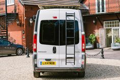 a white van parked in front of a brick building with stairs leading up to it