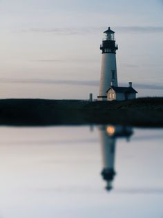 a light house sitting on top of a hill next to water