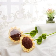 two crocheted sunflowers sitting on top of a bed