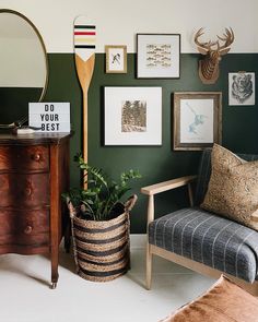 a living room with green walls and pictures on the wall next to a wooden chair