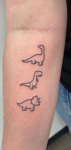 a man's arm with three small dinosaurs on the left side of his arm