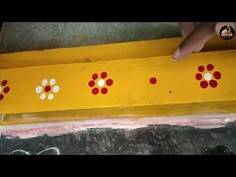 a yellow board with red and white dots painted on it, being held up by someone's hand