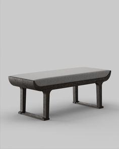 a bench made out of wood and metal with a gray cushion on the top, in front of a grey background