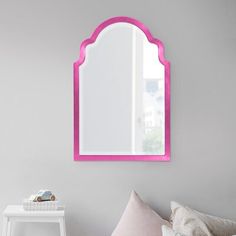 a mirror that is on the wall above a bed in a room with pink accents