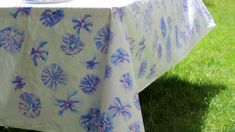 a blue and white table cloth with flowers on it in the middle of some grass