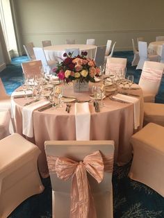 the table is set up with white linens and pink sashes for guests to sit at