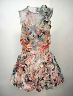 a dress hanging up on a wall in front of a white wall with an abstract painting