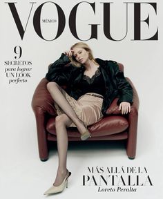 a woman sitting on top of a red chair in front of a magazine cover with her legs crossed