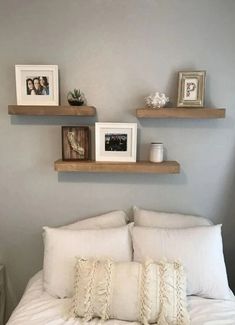 some shelves above a bed with pillows and pictures