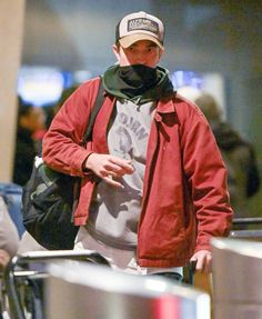 a man in a red jacket and hat walking through an airport